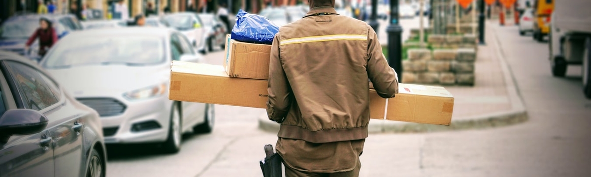 A delivery man standing in the middle of the street with packages